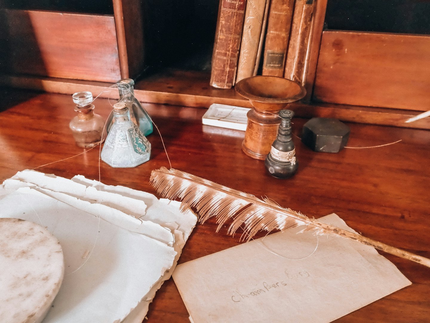A quill pen and antique paper rest on a wooden desk.