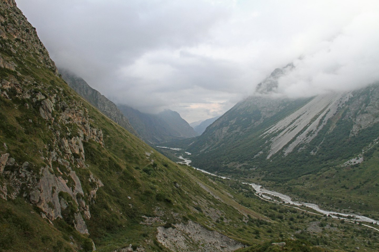 A winding river flows through a steep mountain valley.